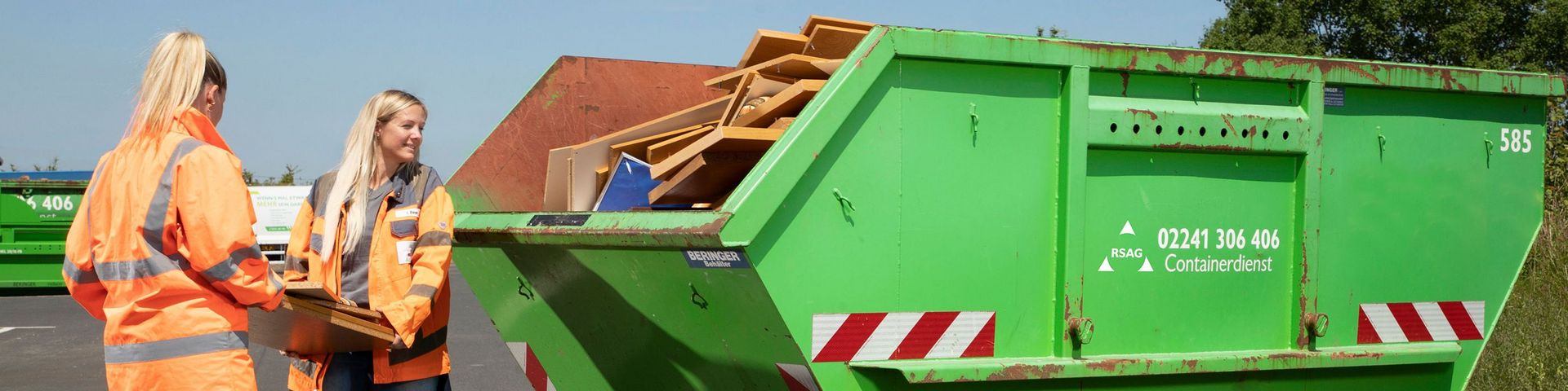 Zwei Mitarbeiterinnen werfen Möbel in Container